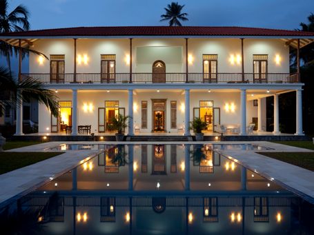 Grand luxury estate home with pool lighting at night